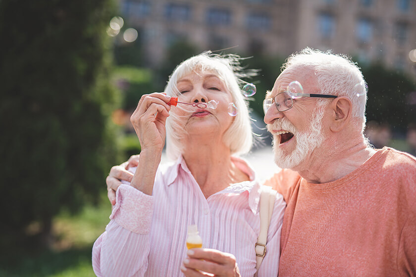 Cheerful lady holding bottle with soap water and blowing bubbles on street Cheerful lady holding bottle with soap water and blowing bubbles on street
