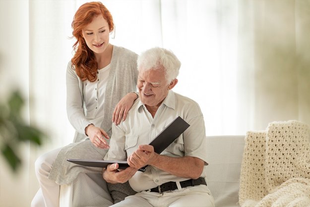 Granddaughter and happy grandfather watching photobook during meeting Granddaughter and happy grandfather watching photobook during meeting