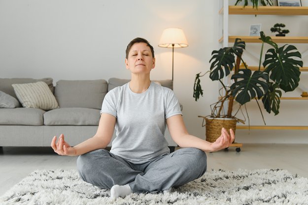 Middle-aged woman doing yoga at home for stretching and being healthy. Middle-aged woman doing yoga at home for stretching and being healthy.