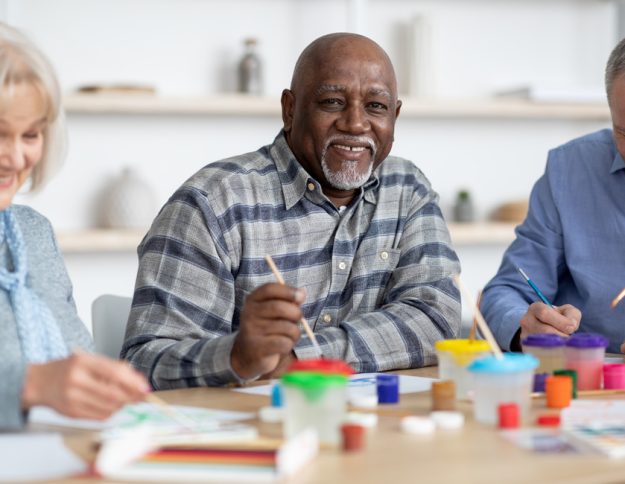 Happy senior black man enjoying painting activity with his friends 6 Benefits Of A Minimalist Life In Bluff View, TX Assisted Living