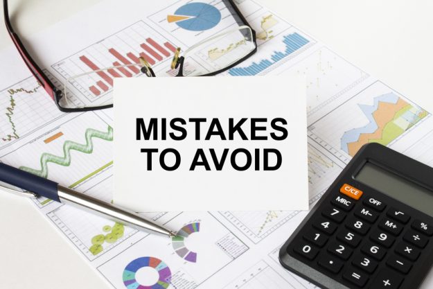 White card with text Mistakes To Avoid it is lies on financial charts with a calculator and eyeglasses 4 Costly Mistakes You Should Avoid When Moving To Retirement Homes In Lower Greenville, TX