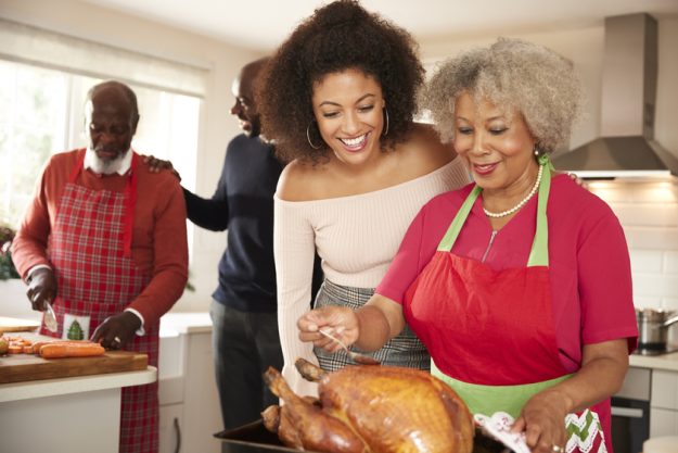Mixed race senior and young adult family members talking in the kitchen while preparing Christmas dinner together, close up The Stress Of Caring For A Loved One: 10 Tips To Keep You Positive