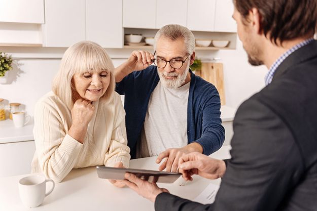 Couple using gadget with real estate agent Couple using gadget with real estate agent