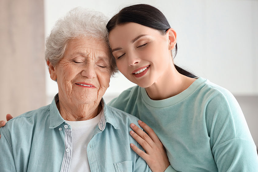 Senior woman with her daughter hugging in kitchen, closeup
