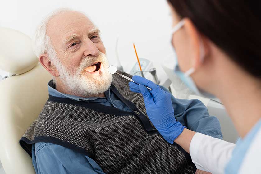 Senior man having teeth examination by dentist in latex gloves with mirror in dental chair Senior man having teeth examination by dentist in latex gloves with mirror in dental chair