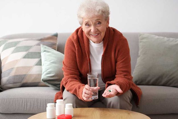 Senior woman with pills and glass of water at home Senior woman with pills and glass of water at home
