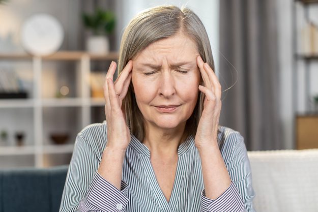 Frustrated senior lady suffering from strong sudden migr