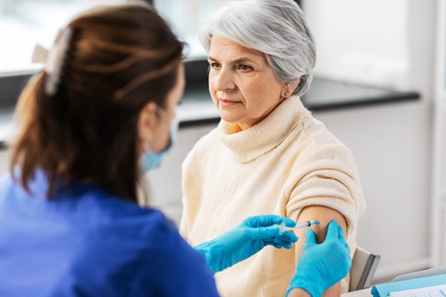 Nurse-with-syringe-making-injection-to-woman Nurse-with-syringe-making-injection-to-woman