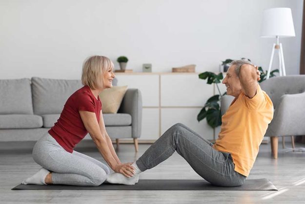 Sporty-senior-lady-exercising-with-her-husband-at-home Sporty-senior-lady-exercising-with-her-husband-at-home