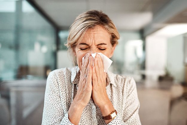 Could this be the flu. a mature businesswoman blowing her nose Could this be the flu. a mature businesswoman blowing her nose