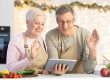Senior Couple Waving Hello To Tablet Making Video call
